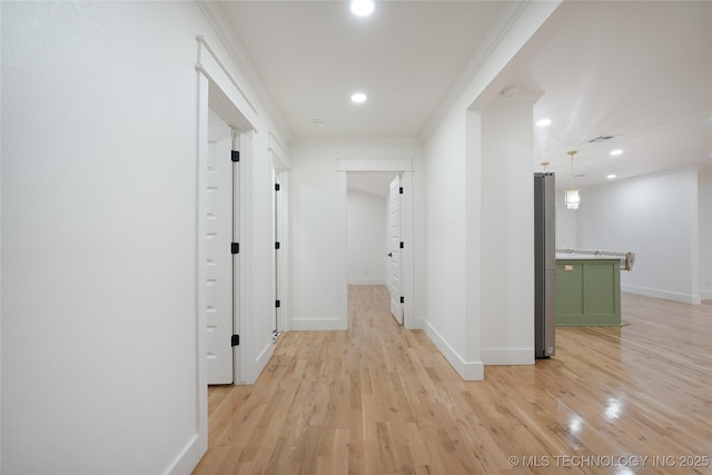 corridor featuring light wood-style floors, baseboards, crown molding, and recessed lighting