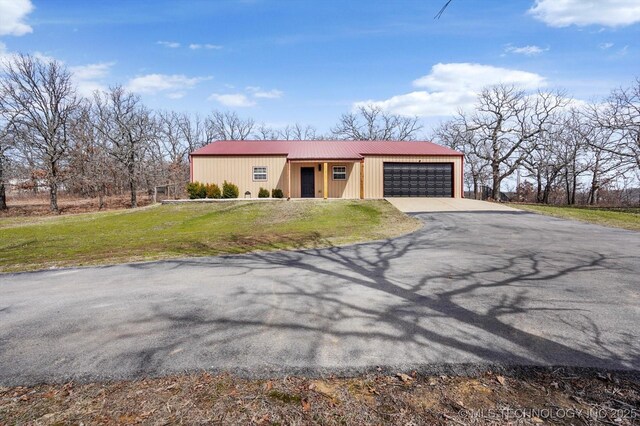 view of front of property with metal roof, a front lawn, an attached garage, and driveway