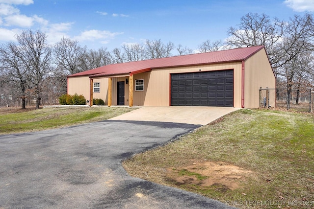 view of front of property featuring metal roof, fence, and aphalt driveway