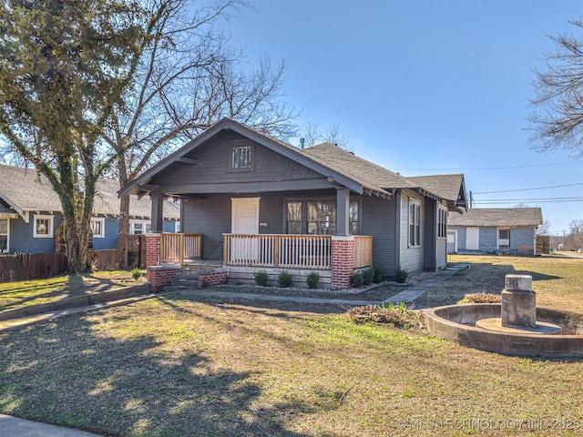 bungalow featuring a shingled roof, a front yard, and covered porch