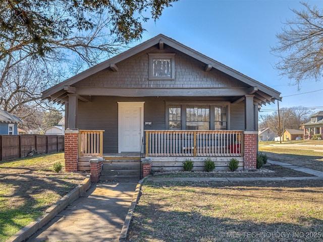 view of front of home featuring a front yard, covered porch, and fence