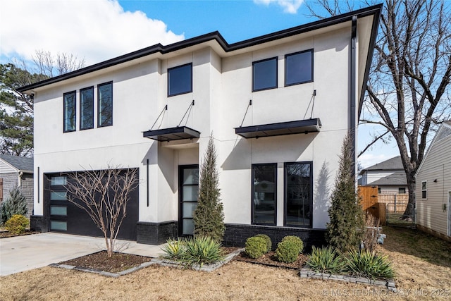 view of front of property with an attached garage, brick siding, fence, concrete driveway, and stucco siding