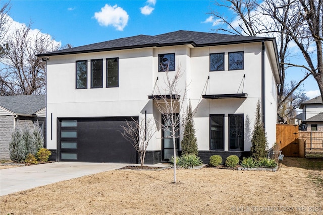 view of front of home with driveway, a garage, roof with shingles, fence, and stucco siding