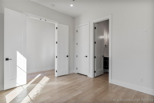 unfurnished bedroom with light wood finished floors, baseboards, ensuite bathroom, and recessed lighting