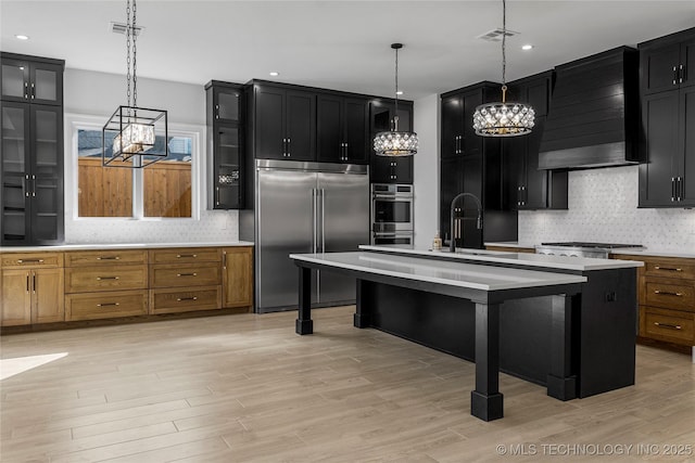 kitchen with wall chimney exhaust hood, appliances with stainless steel finishes, and light countertops