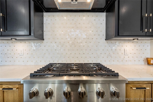 kitchen featuring tasteful backsplash, stainless steel gas stovetop, extractor fan, and dark cabinetry