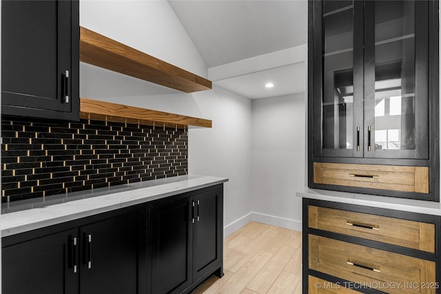 bar with vaulted ceiling, baseboards, light wood-style flooring, and decorative backsplash