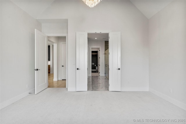 unfurnished bedroom featuring high vaulted ceiling, carpet, baseboards, and a notable chandelier