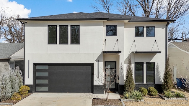 view of front of house featuring roof with shingles, driveway, an attached garage, and stucco siding