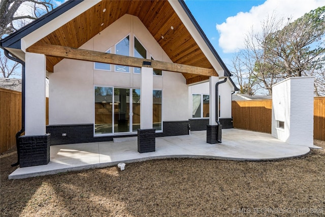 rear view of house featuring a patio, fence, and stucco siding