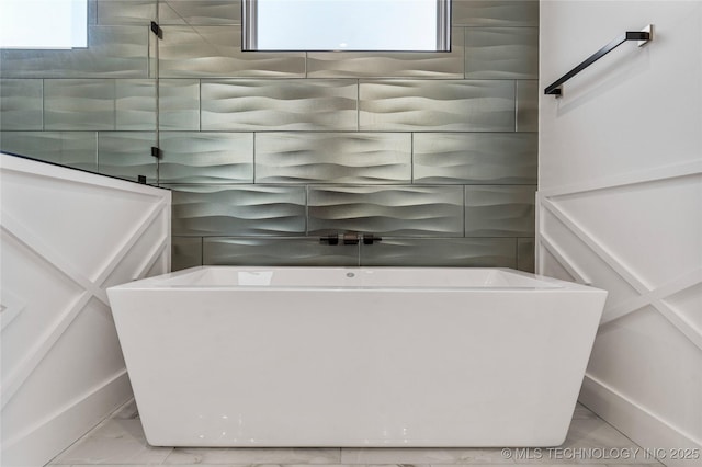 bathroom with marble finish floor and a soaking tub