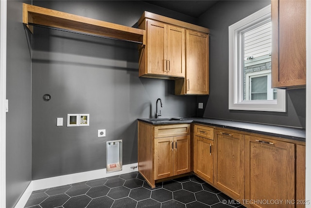 kitchen with dark countertops, baseboards, brown cabinets, and a sink