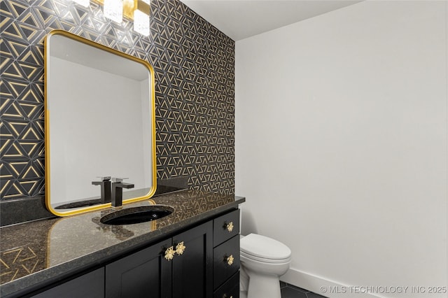 bathroom featuring toilet, baseboards, and vanity