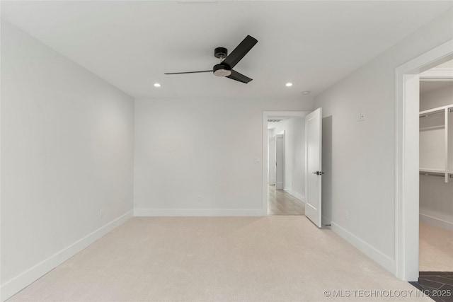 unfurnished bedroom featuring carpet, a spacious closet, baseboards, and recessed lighting