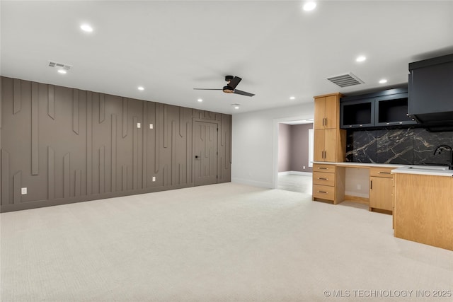 unfurnished living room featuring ceiling fan, recessed lighting, light colored carpet, a sink, and visible vents