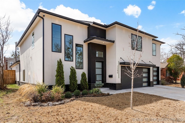 modern home featuring driveway, fence, an attached garage, and stucco siding