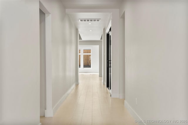 hall featuring baseboards and visible vents