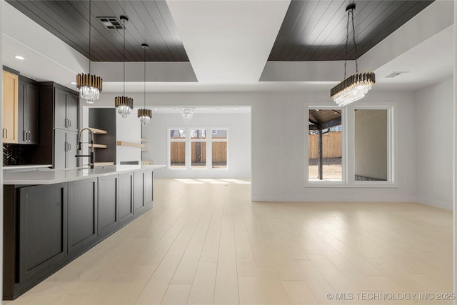 kitchen with a wealth of natural light, a raised ceiling, light countertops, and open floor plan