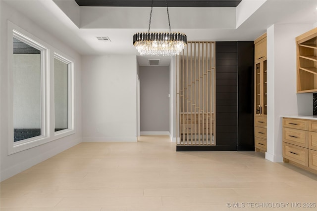 interior space with a chandelier, light wood-type flooring, visible vents, and baseboards