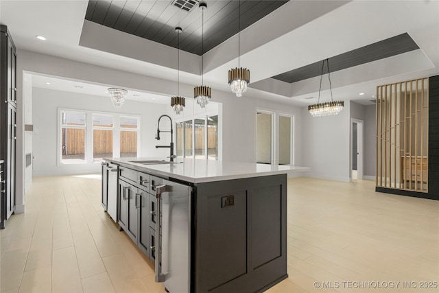 kitchen featuring hanging light fixtures, beverage cooler, a tray ceiling, and a sink