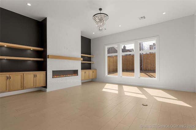 unfurnished living room featuring light wood finished floors, a fireplace, visible vents, and built in shelves