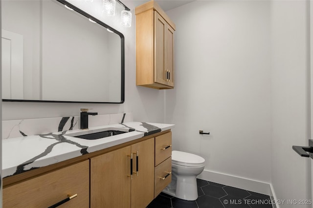 half bathroom featuring toilet, baseboards, vanity, and tile patterned floors