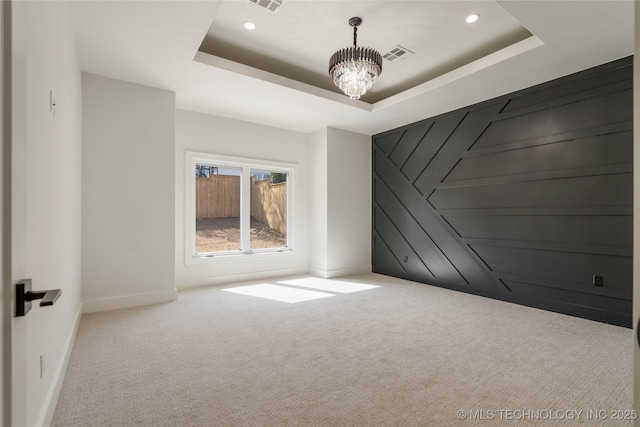 carpeted empty room featuring a chandelier, a tray ceiling, visible vents, and recessed lighting