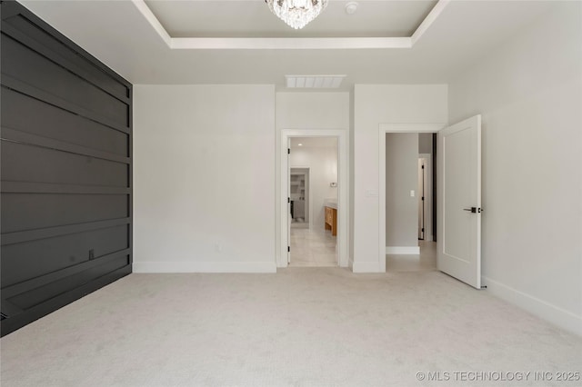 unfurnished bedroom with a raised ceiling, carpet flooring, visible vents, and baseboards