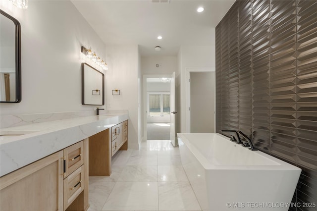 full bathroom with double vanity, visible vents, marble finish floor, a freestanding tub, and recessed lighting