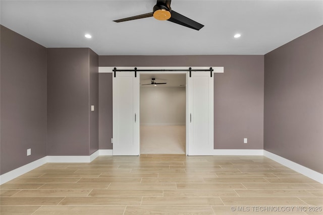 interior space with a barn door, wood finish floors, and a ceiling fan