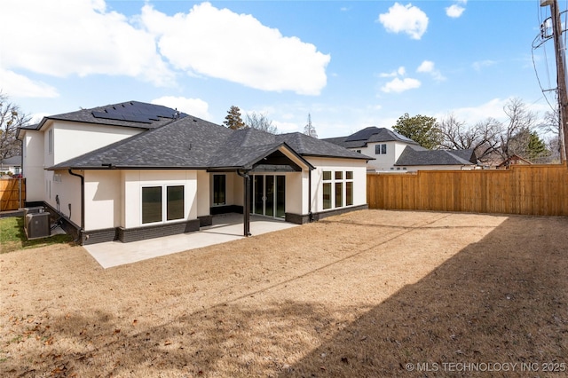 rear view of property with a patio, stucco siding, a fenced backyard, central air condition unit, and brick siding