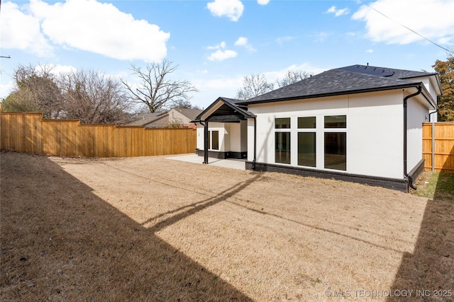 rear view of property featuring a fenced backyard, roof with shingles, a patio, and stucco siding