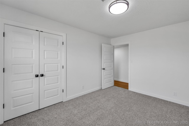 unfurnished bedroom featuring baseboards, a closet, carpet floors, and a textured ceiling