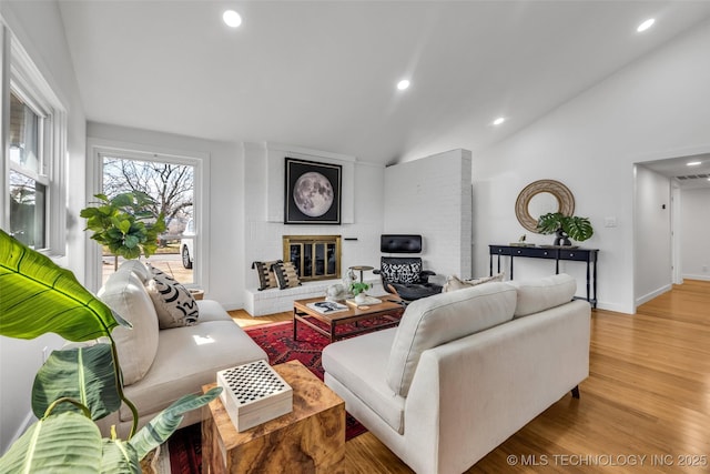 living room featuring baseboards, vaulted ceiling, recessed lighting, a fireplace, and wood finished floors