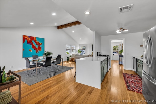 kitchen featuring a healthy amount of sunlight, visible vents, lofted ceiling with beams, light wood-style flooring, and appliances with stainless steel finishes