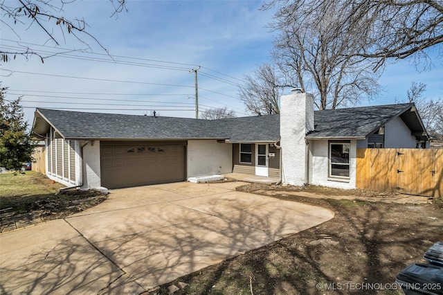 view of front of home with driveway, fence, a garage, brick siding, and a chimney