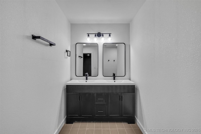 bathroom featuring tile patterned flooring, double vanity, baseboards, and a sink