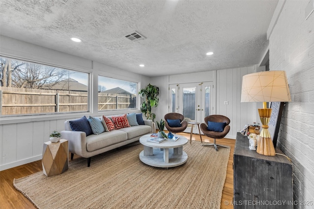 living area featuring wood finished floors, visible vents, recessed lighting, french doors, and a textured ceiling