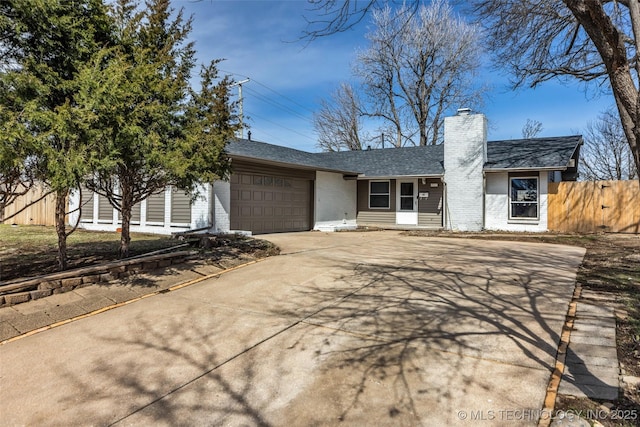 view of front of home with brick siding, fence, a chimney, a garage, and driveway