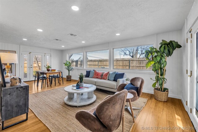 living room with a wealth of natural light, a textured ceiling, and wood finished floors