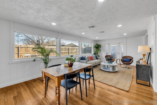 dining space featuring wood finished floors, visible vents, and a textured ceiling