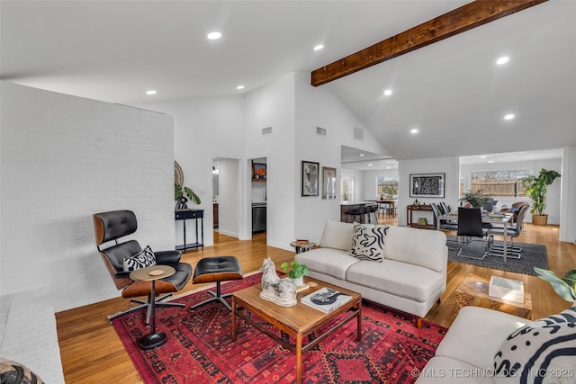 living area featuring beamed ceiling, high vaulted ceiling, visible vents, and wood finished floors