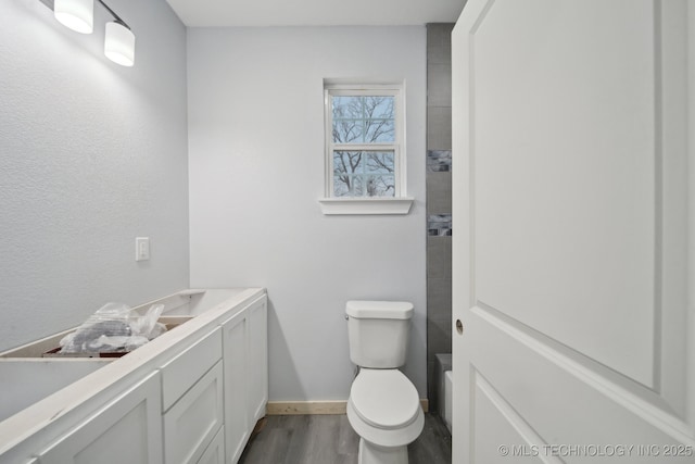 bathroom featuring vanity, toilet, wood finished floors, and baseboards