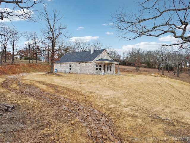 rear view of house featuring stone siding and a chimney