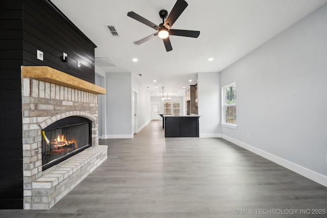 7890 N Oak Dr, Beggs, OK 74421 - unfurnished living room with wood finished floors, a ceiling fan, a brick fireplace, visible vents, and baseboards