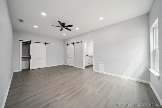7890 N Oak Dr, Beggs, OK 74421 - unfurnished bedroom with wood finished floors, a barn door, visible vents, recessed lighting, and baseboards