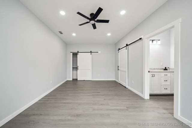 7890 N Oak Dr, Beggs, OK 74421 - unfurnished bedroom featuring light wood finished floors, a barn door, baseboards, and recessed lighting