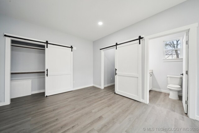 7890 N Oak Dr, Beggs, OK 74421 - unfurnished bedroom featuring recessed lighting, a barn door, baseboards, and wood finished floors