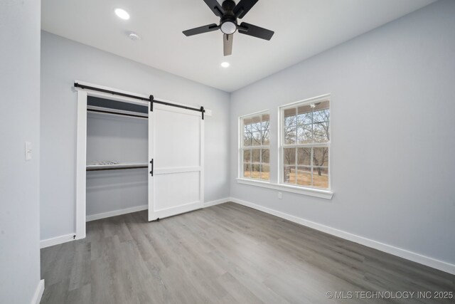 7890 N Oak Dr, Beggs, OK 74421 - unfurnished bedroom featuring a closet, recessed lighting, a barn door, baseboards, and wood finished floors