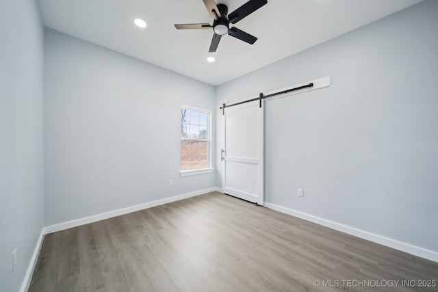 7890 N Oak Dr, Beggs, OK 74421 - unfurnished bedroom featuring recessed lighting, a barn door, baseboards, and wood finished floors